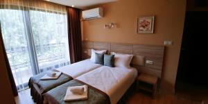 a bedroom with a large bed with two towels on it at Garden Guest House in Sandanski