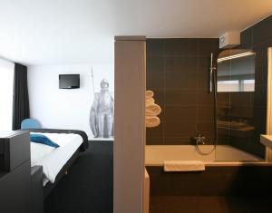 ein Hotelzimmer mit einem Bett und einem Bad mit einer Dusche in der Unterkunft Hotel De Groene Hendrickx in Hasselt