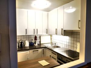 kuchnia z białymi szafkami i drewnianym stołem w obiekcie Seewohnung am Ossiacher See direkt an der Gerlitzen w Villach