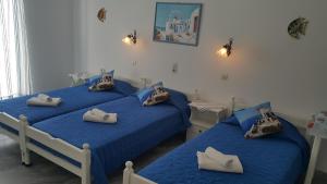 2 camas en una habitación con sábanas y almohadas azules en Augusta Studios & Apartments, en Naousa