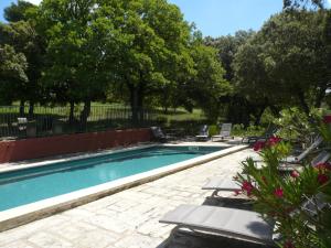 una piscina con tumbonas y sillas en un patio en Chambres d'hôtes de la gardy, en Eyragues