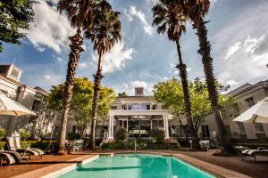 uma piscina em frente a um edifício com palmeiras em Garden Court Morningside Sandton em Joanesburgo