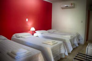 two beds in a room with a red wall at Hotel Pousada Ipitanga IV in Lauro de Freitas