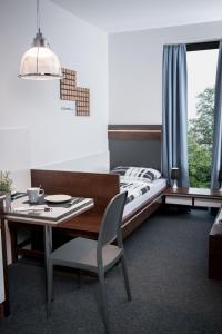 ein Schlafzimmer mit einem Bett und einem Tisch mit einem Stuhl in der Unterkunft Triumph Inn Pension in Rangsdorf