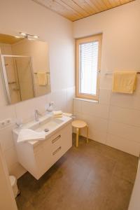 ein weißes Badezimmer mit einem Waschbecken und einem Spiegel in der Unterkunft Gästehaus Gritsch in Hard