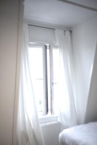 a bedroom with a window with white curtains at Cozy Pijp Apartment Amsterdam in Amsterdam