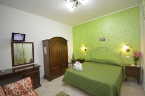 - une chambre dotée d'un lit vert avec un ours en peluche dans l'établissement tre passi dal mare, à San Vito Lo Capo