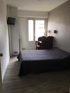 a bedroom with a bed and a table and a window at Firmhotel le 37 in Firminy