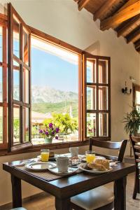 una mesa de madera con comida en una habitación con ventanas en So Nice Hotel, en Marathokampos