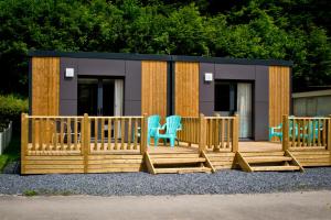 a tiny house with chairs and a deck at Taos Single - Camping Du Nord in Dirbach