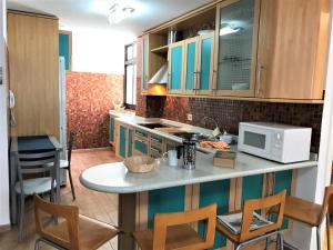 - une cuisine avec un comptoir avec des chaises et un four micro-ondes dans l'établissement Nature Vista Agaete & Parking, à Agaete