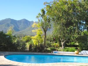a swimming pool in a garden with mountains in the background at Malvern Manor Country Guest House in George