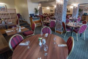 a restaurant with wooden tables and purple chairs at Alexandra Hotel in Fort William
