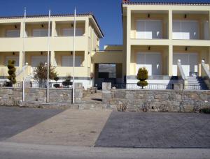 a large yellow building with a stone wall in front of it at Evgatis Hotel in Kondiás