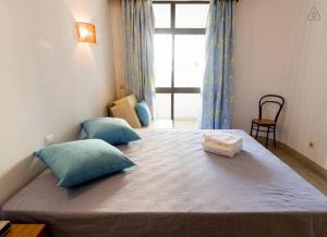 Roja- PéにあるApartamento T1 a 250 metros da Praia - Albufeiraのベッドルーム1室(大型ベッド1台、青い枕、窓付)