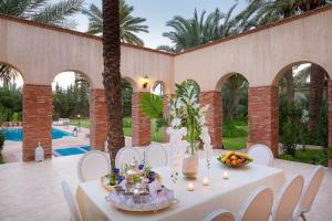 Domaine Rosaroum في مراكش: طاولة عليها كراسي بيضاء وطاولة عليها فاكهة