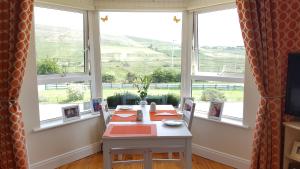 a table and chairs in a room with windows at An Charraig Ban on the wild Atlantic way F94WT02 in Ardara