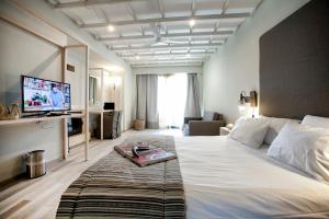 a hotel room with a large bed with a television at Rigas Boutique Hotel & Spa in Afitos