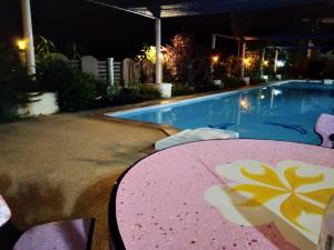 a table and chairs next to a swimming pool at night at Peace Pool Resort in Khun Han