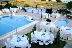 a group of tables and chairs next to a swimming pool at Evgatis Hotel in Kondiás