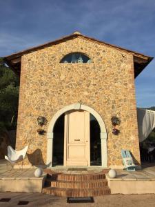 un edificio de piedra con una puerta y una silla en Valuable rustic Tuscan swimming pool, breathtaking view of Camaiore, en Camaiore