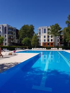 una piscina con sillas y edificios en el fondo en Apartament pomarańczowy z basenem,sauną-blisko morza. en Kołobrzeg