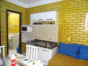 cocina con sofá y cocina con ladrillos amarillos en Apto Duplex Bombinhas, en Bombinhas