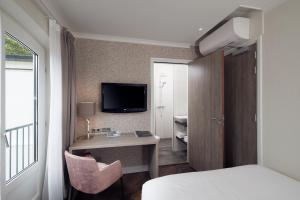 a hotel room with a bed and a desk and a tv at Hotel De Lindeboom in Den Burg