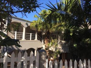 a white fence in front of a white house at Knysna N2 Lodge in Knysna