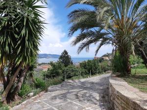 un sentiero con palme e l'oceano sullo sfondo di Casa Isabelle Mel a La Spezia