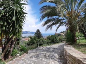 a path with palm trees and the ocean in the background at Casa Isabelle Mel in La Spezia