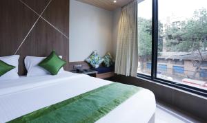 a bedroom with a large bed and a large window at Treebo Trend Olive Nest in Mumbai