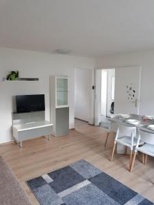 a white living room with a table and a tv at SUNSHINE Apartments Rust-Ringsheim in Ringsheim