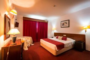 a hotel room with a bed and a red curtain at Hotel Arangues in Setúbal