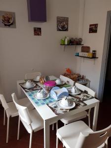 Biały stół z białymi krzesłami i płytami w obiekcie Il Cucù B&B w mieście Frascati