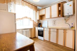 eine Küche mit Holzschränken und einem Holztisch in der Unterkunft Апартаменты в самом центре in Mykolajiw