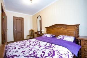 ein Schlafzimmer mit einem Bett mit einer lila und weißen Bettdecke in der Unterkunft Апартаменты в самом центре in Mykolajiw