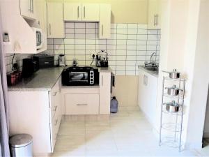 a small kitchen with white cabinets and a microwave at 102 Siyayi in Mtunzini