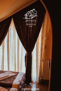 a bedroom with a bed with a window with curtains at Pensiunea Renata in Boghiş