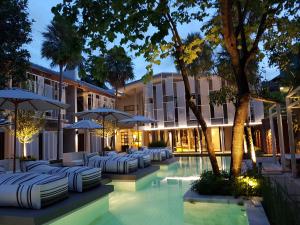 a hotel swimming pool with white chairs and umbrellas at Treevana Club Chiangmai in Chiang Mai