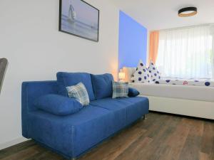 Sofá azul en la sala de estar con ventana en Ferienapartement Boot, en Meersburg