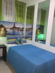 a bedroom with a blue bed in a room with windows at Alegria Hostal in Santiago de los Caballeros