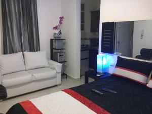 a living room with a couch and a table with remote controls at Alegria Hostal in Santiago de los Caballeros
