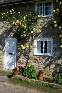 a stone house with a blue door and flowers at The Cottage Abbotsbury in Abbotsbury