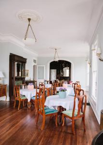 een eetkamer met witte tafels en houten stoelen bij Carr Mansion in Galveston