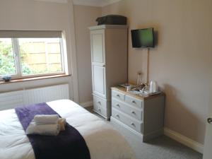 a bedroom with a bed and a dresser with a television at The Old Wash House in Fakenham