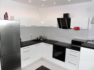 eine Küche mit weißen Schränken und einem Kühlschrank aus Edelstahl in der Unterkunft MOne - fajny apartament w centrum Wrocławia in Breslau