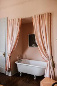een badkamer met een bad en gordijnen bij Carr Mansion in Galveston