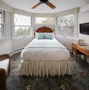 a bedroom with a bed and a desk and windows at Cape Arundel Inn and Resort in Kennebunkport +64 photos