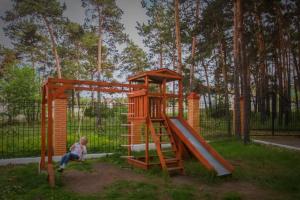 a boy sitting next to a wooden play structure at Hotel Nurlytau in Borovoye